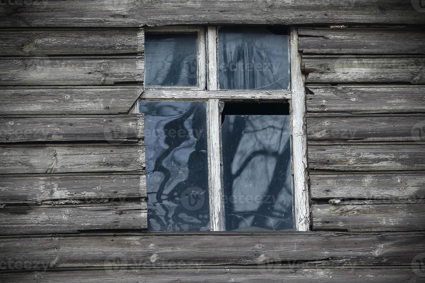 Old white frame wooden window with dirty broken glass photo