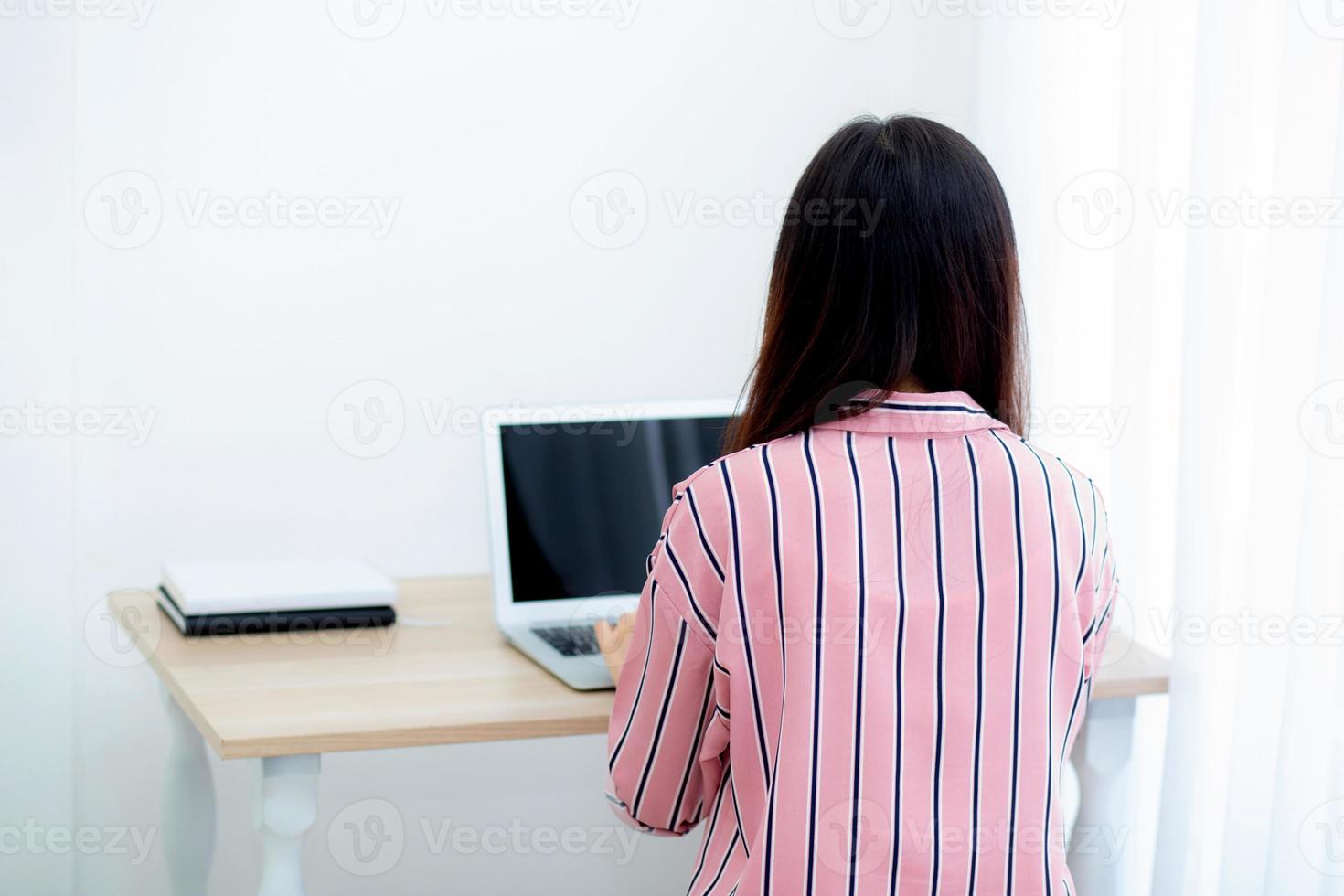 Young asian woman working on laptop computer sitting at living room. photo