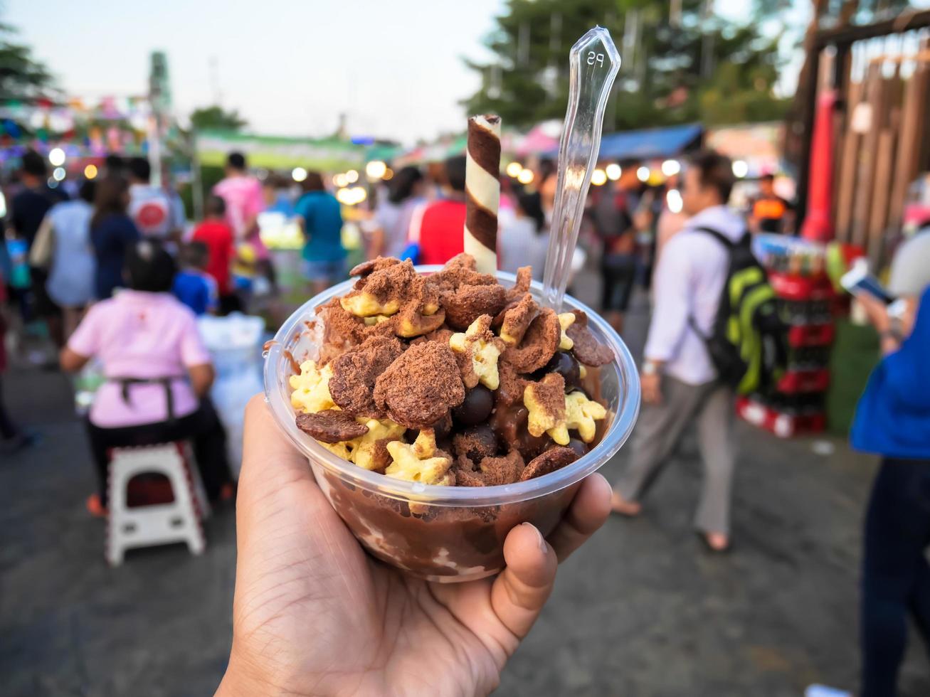 Left hand holding a bowl with desserts, sweets sold at the festival, Thailand photo