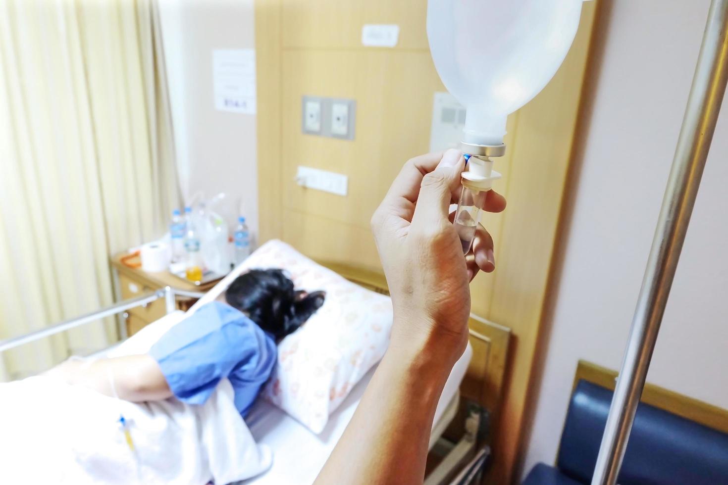 la mano ajusta un caudal intravenoso. pacientes mujeres perforación de solución salina en el hospital. foto