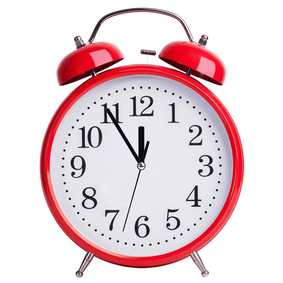 Red alarm clock shows five minutes to twelve photo