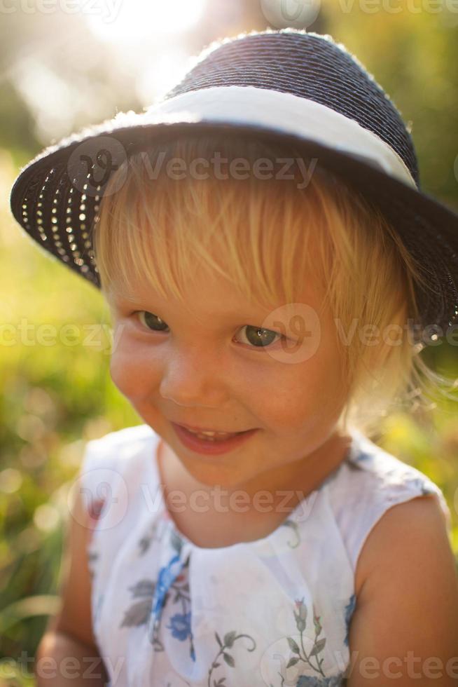 Cute little blonde smiling girl in a blue hat photo