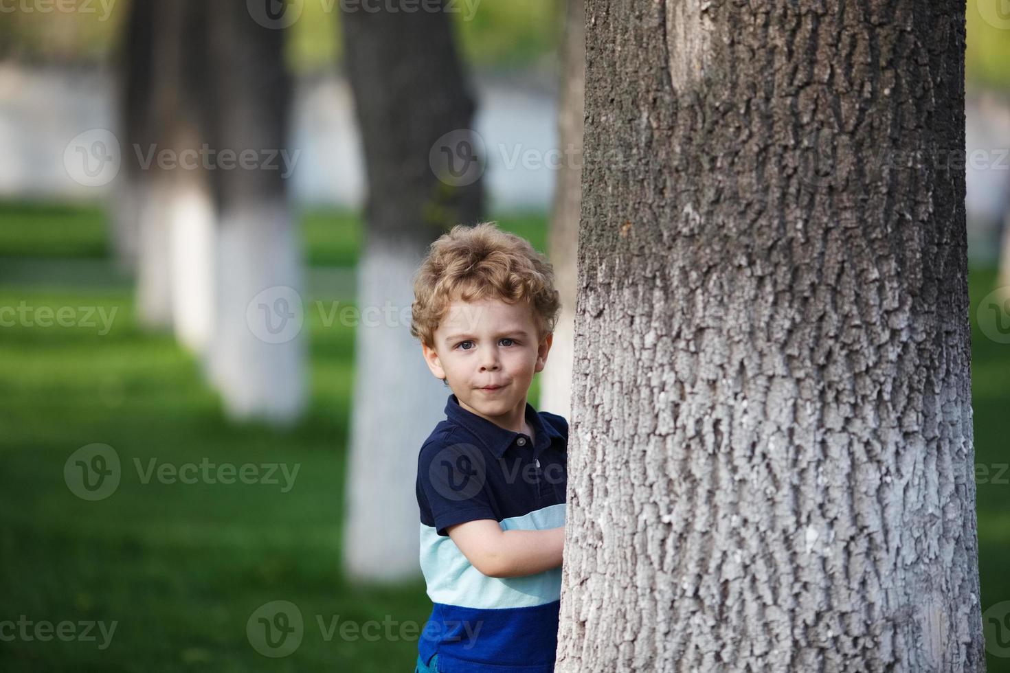 niño se esconde detrás de un árbol foto