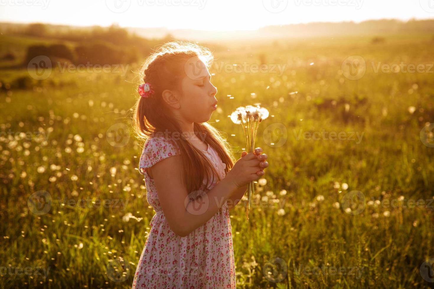 Girl blowing a bouquet of dandelions photo