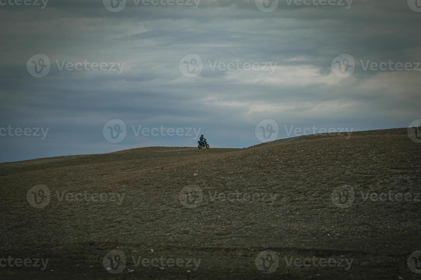 The biker rides motorcycle on mountains photo