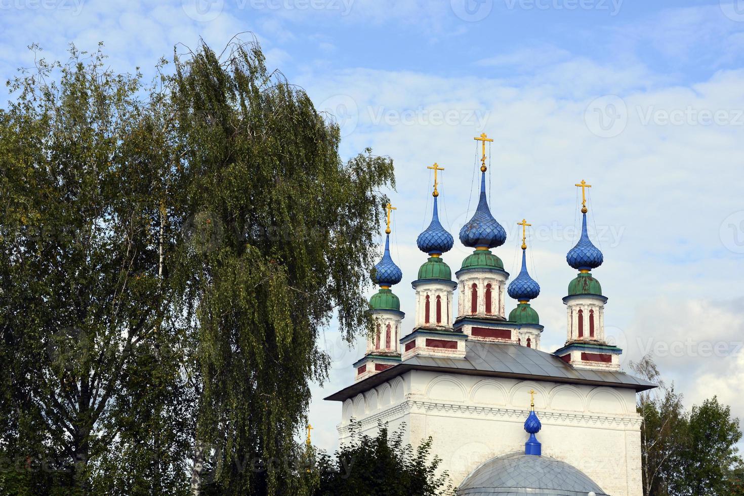 Church domes with crosses against the blue sky. White stone temple in the Russian village. photo
