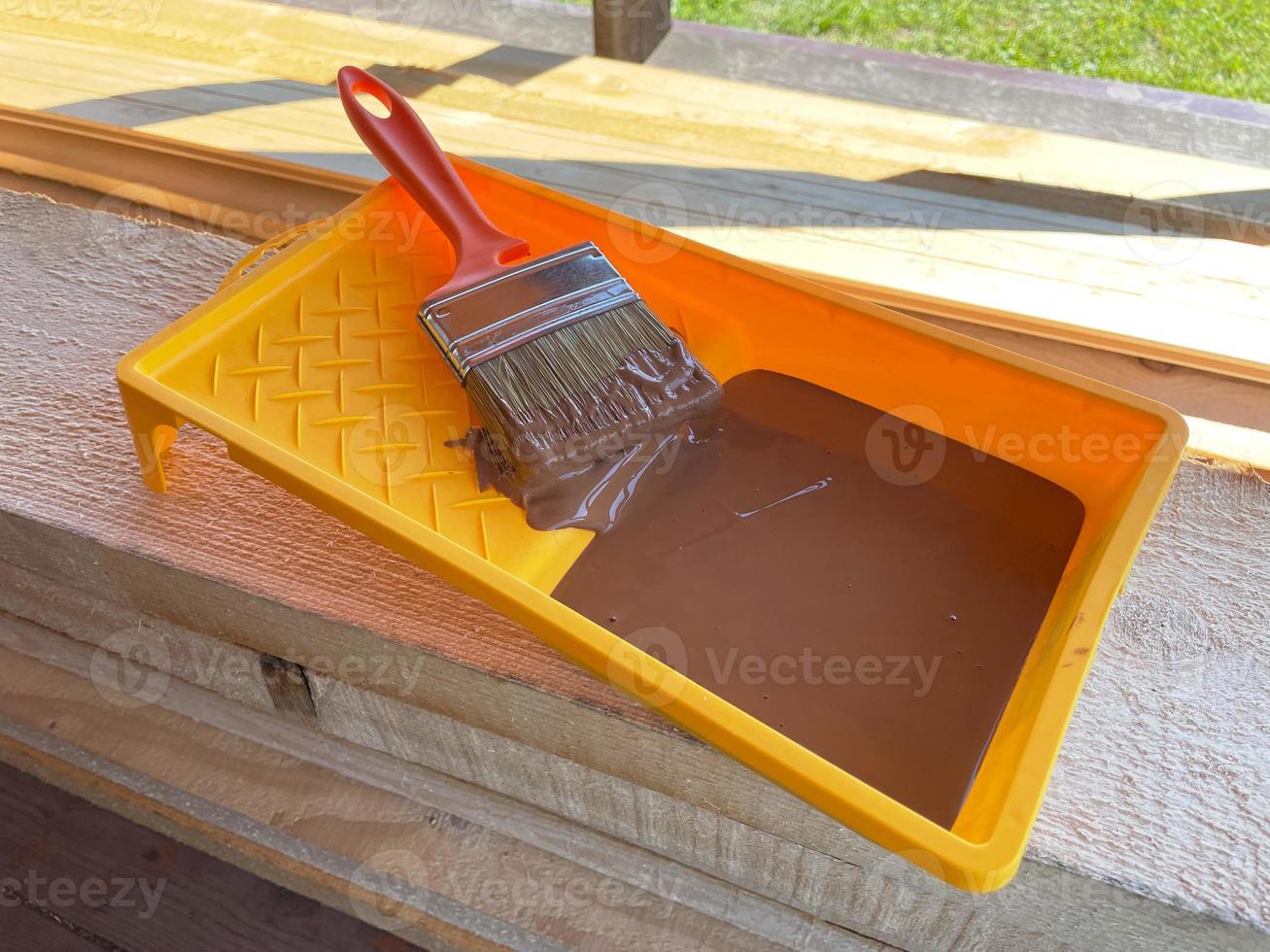 Yellow tray of green paint with brush on wooden background photo