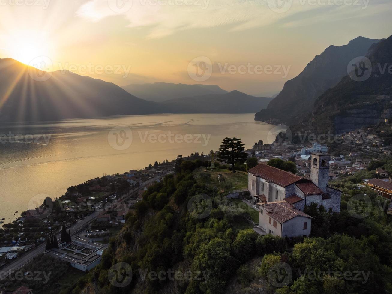 Vista aérea de una antigua iglesia con vistas al lago iseo paisaje desde una colina al atardecer foto