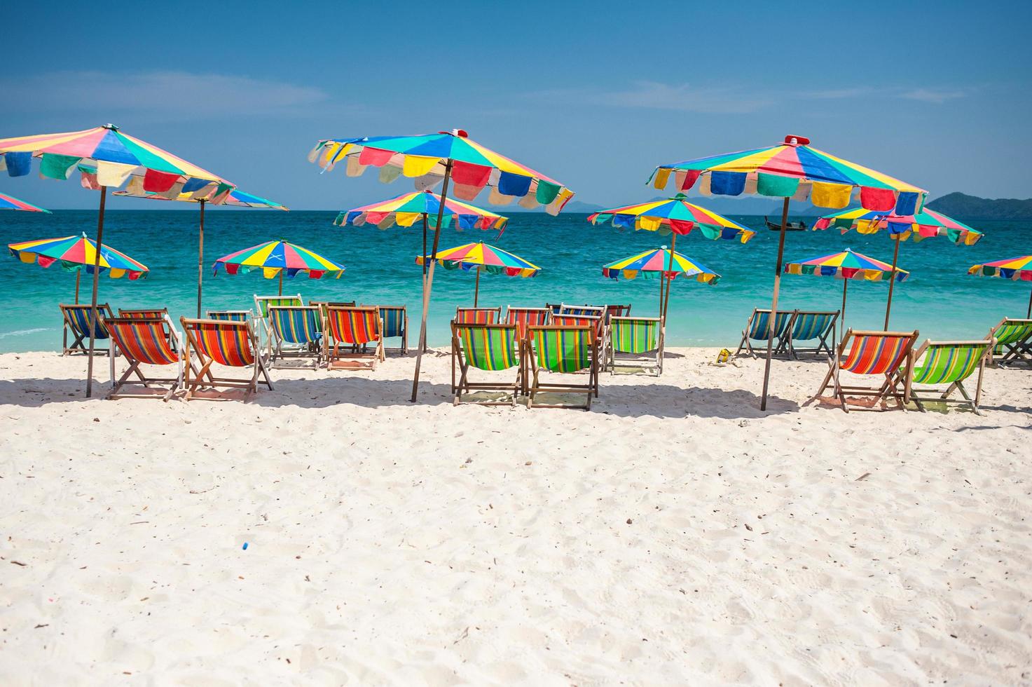 Silla de playa bajo la sombrilla de colorido en la playa de Phuket, Tailandia foto