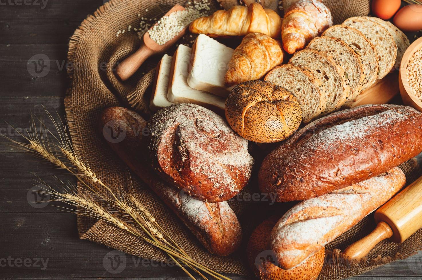 diferentes tipos de pan con cereales integrales de nutrición sobre fondo de madera. comida y panadería en concepto de cocina. delicioso desayuno gouemet y comida. carbohidratos comida orgánica cocina casera foto