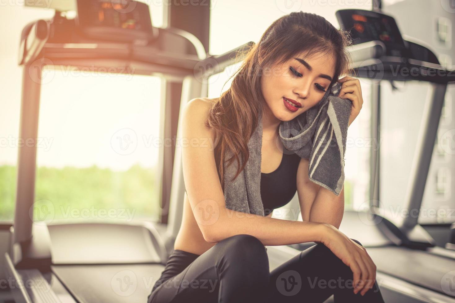 mujer suda con una toalla durante el descanso en el gimnasio con equipo  para correr. concepto de belleza y relajación. tema de gimnasio y  entrenamiento físico 3518197 Foto de stock en Vecteezy