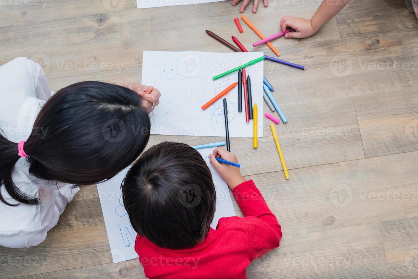 Group of preschool student and teacher drawing on paper in art class. Back to school and Education concept. People and lifestyles theme.  Room in nursery photo