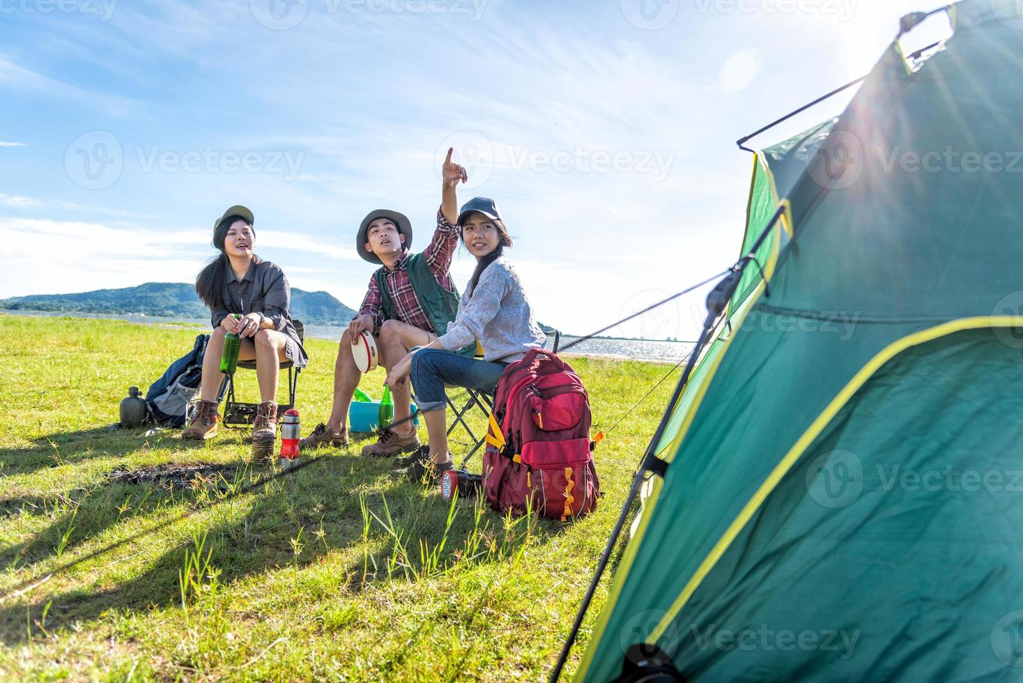 grupo de excursionistas que miran el punto de vista de la atracción en el campo del prado con el fondo de la montaña y del lago. concepto de personas y estilos de vida. tema de senderismo y viajes. tres personas con mochila. primer plano de la tienda foto