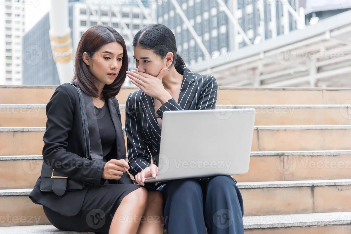 las mujeres de negocios chismean mientras usan la computadora portátil en el exterior. concepto de negocio y compañero de trabajo foto