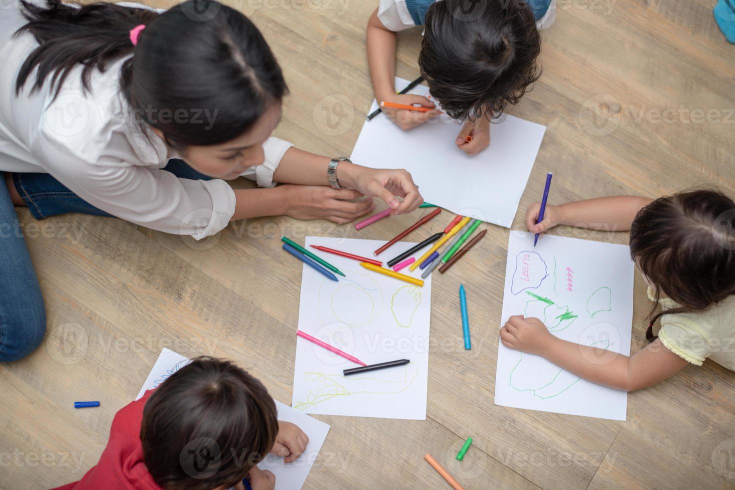Grupo de estudiantes de preescolar y maestros de dibujo en papel en la clase de arte. volver al concepto de escuela y educación. tema de personas y estilos de vida. habitación en vivero foto