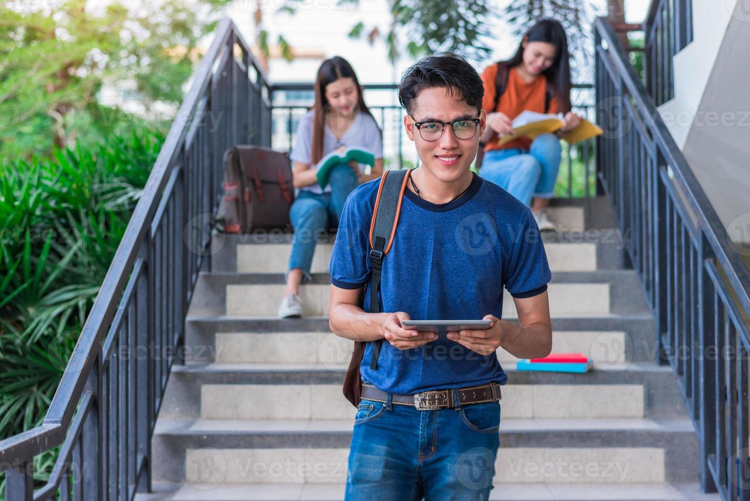 Three Asian young campus students enjoy tutoring and reading books together at stair. Friendship and Education concept. Campus school and university theme. Happiness and funny of learning in college photo