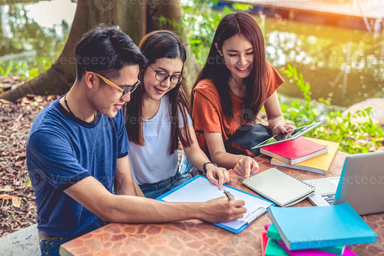 Group of Asian college student reading books and tutoring special class for exam on table at outdoors. Happiness and Education learning concept. Back to school concept. Teen and people theme photo