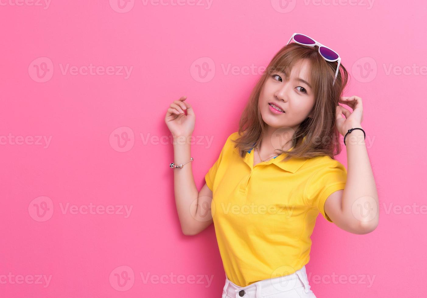 mujer de belleza posando con gafas de sol delante de fondo de pared rosa. concepto de verano y vintage. estilo de vida de felicidad y tema de retrato de personas. tono lindo y pastel foto