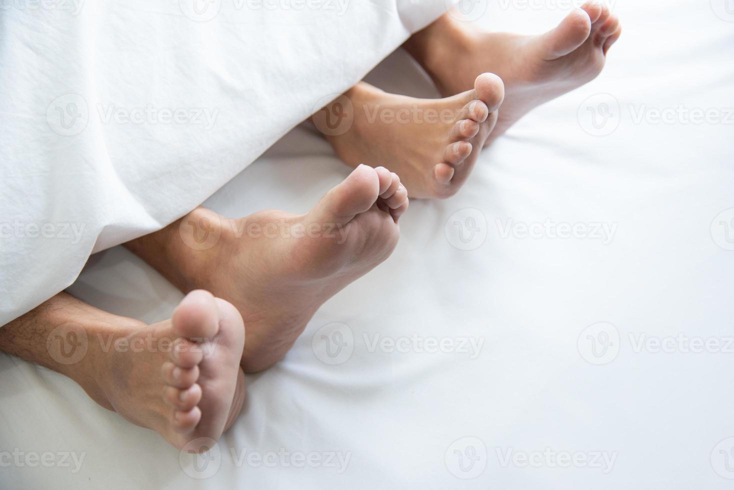 Close up of couple barefoot under blanket in bedroom in honeymoon vacation holiday in long weekend at home. Relaxation of sexual and romantic people after wedding ceremony. Valentines day love theme photo