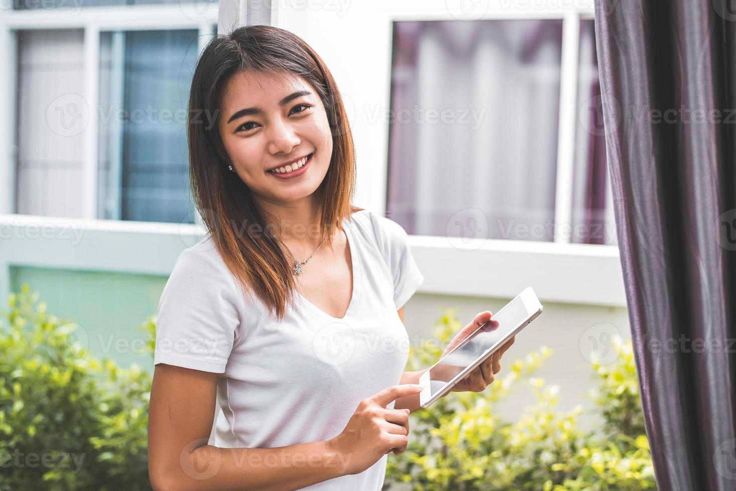 Beauty Asian woman portrait looking camera and using tablet for checking order from customers at home. Business and Delivery transportation concept. Logistic service and Product packing theme photo