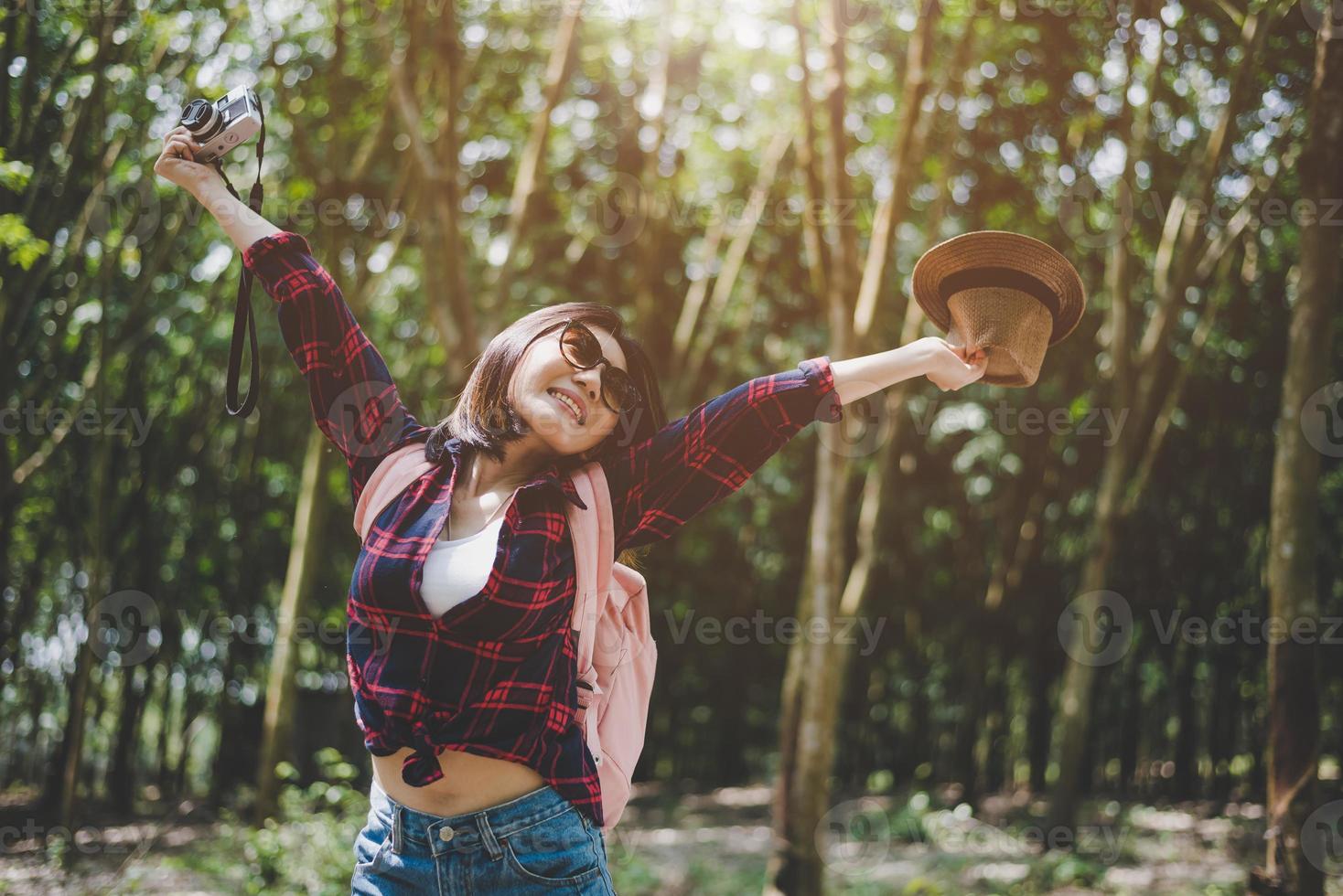 Happiness Asian traveler woman in forest with spread arms and enjoy fresh air. Relax time and Adventure concept. Vacation and Holiday concept. Woods and countryside background theme photo