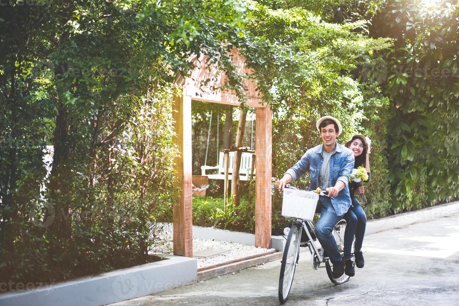 Happy couple riding bicycle together in romantic view park background. Valentine's day and wedding honeymoon concept. People and lifestyles concept photo