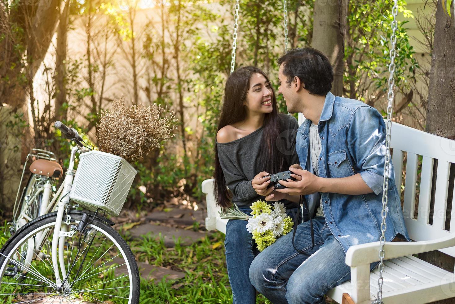 Pareja asiática teniendo contacto visual como momento romántico en un banco en el parque natural con bicicleta. concepto de personas y estilos de vida para el día de San Valentín y la ceremonia de la boda. amor a primera vista tema foto