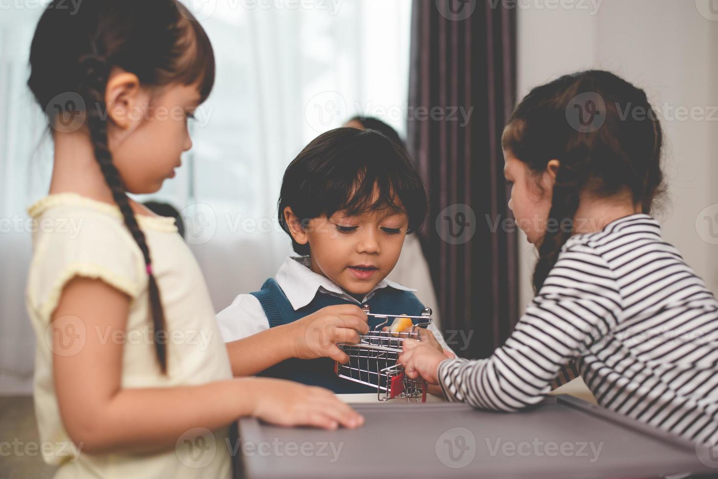 Boy fighting for toys with her sisters. Family and children concept. Conflict and quarrel theme. Thee people in home photo