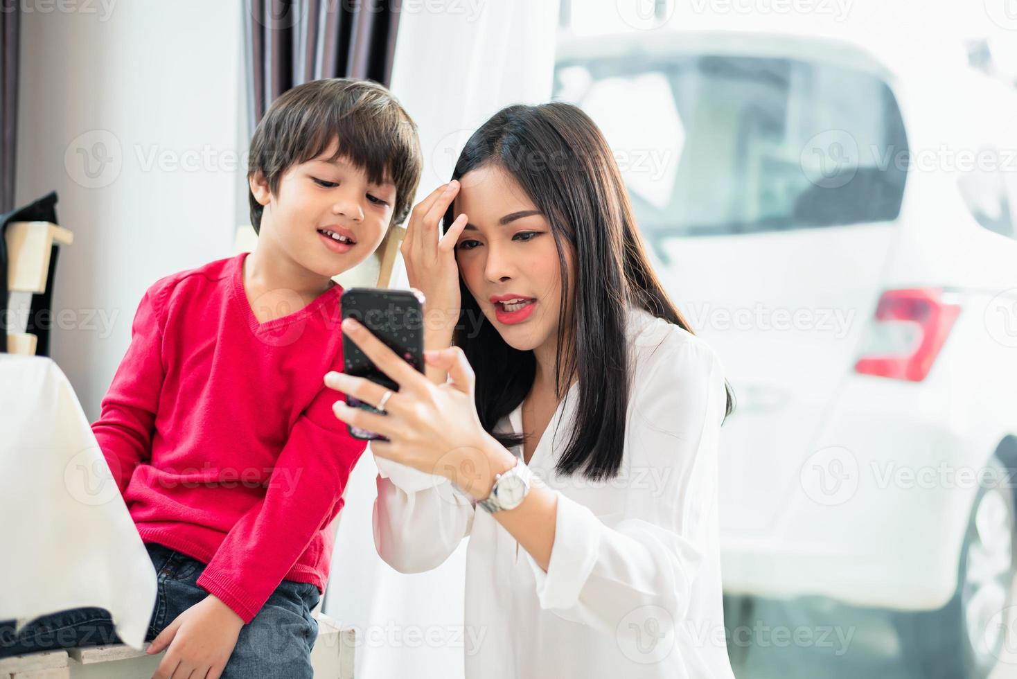 Mom and her child using and looking into smartphone together. People and Technology concept. Education and Learning theme photo