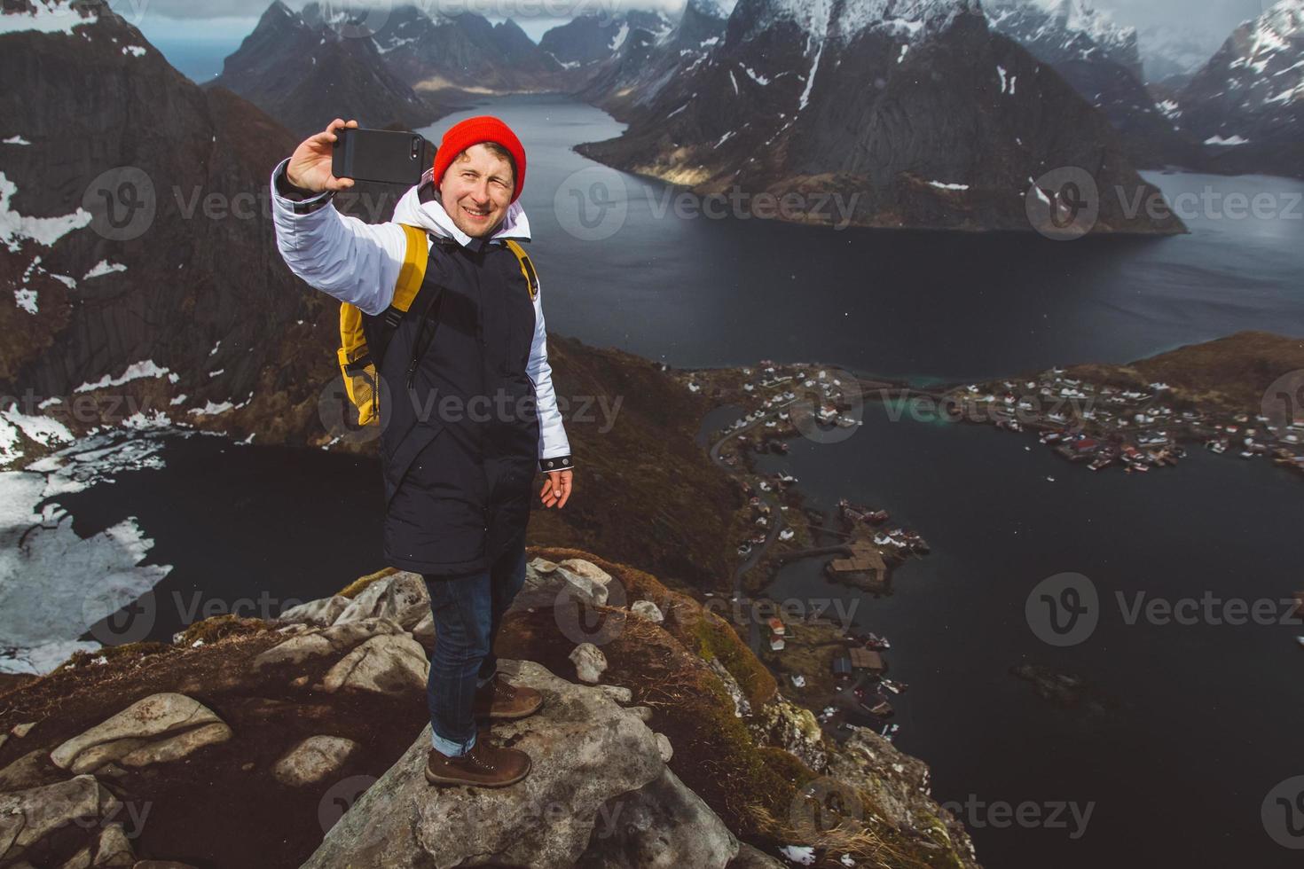 Hombre viajero tomando una foto autorretrato con un smartphone senderismo en la cresta de la montaña en Noruega