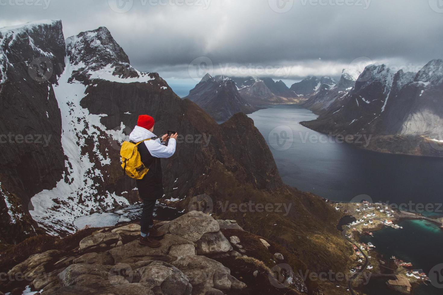 Man traveler taking photo with a smartphone hiking on mountain ridge in Norway