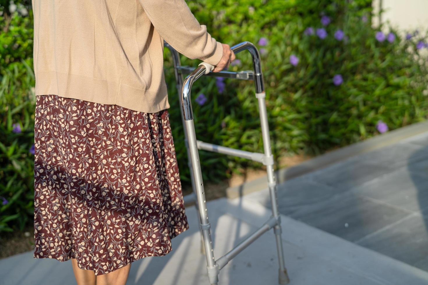 Asian senior or elderly old lady woman patient walk with walker in park with copy space, healthy strong medical concept photo