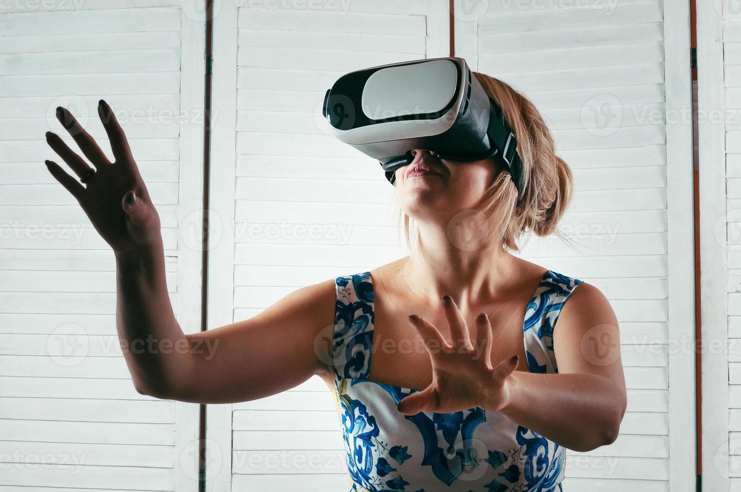 woman wearing VR glasses, pointing her hand in the air photo