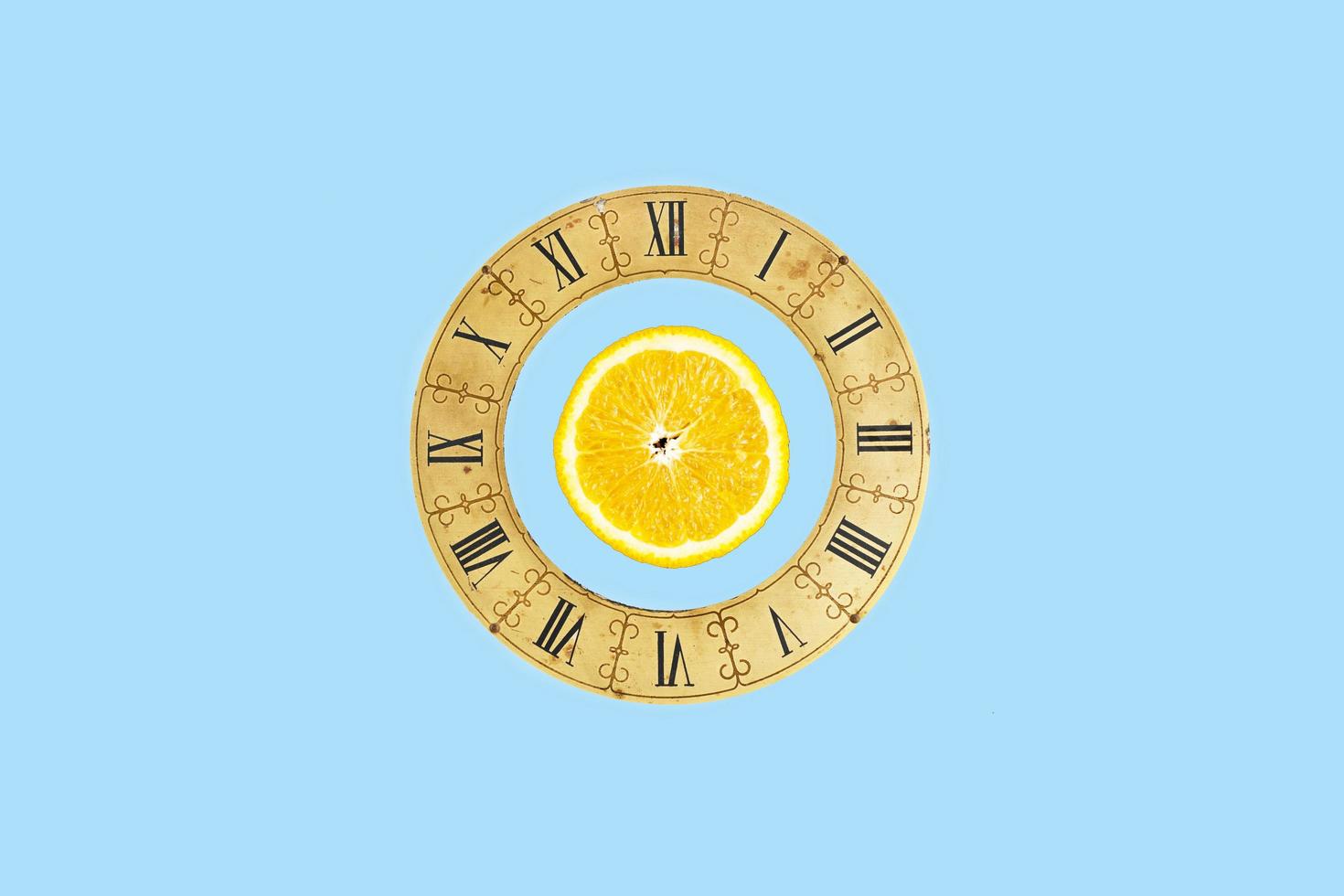 Simple concept with a slice orange and a vintage clock dial on blue background photo