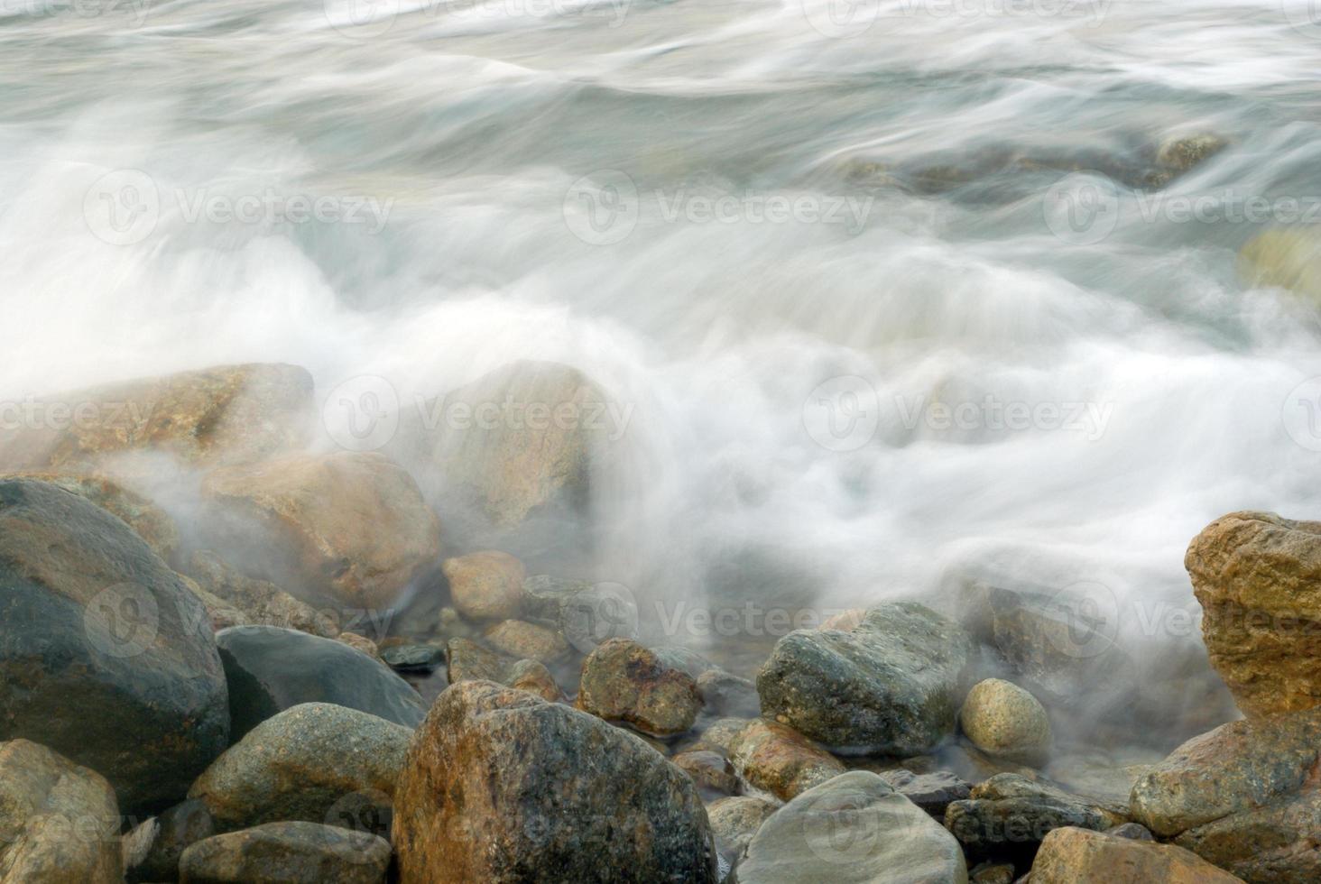 turbulencia de agua de mar y rocas en la costa foto