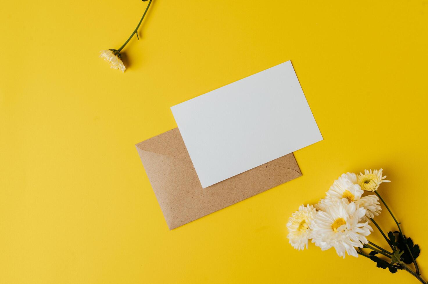 A blank card with envelope and flower is placed on yellow background photo