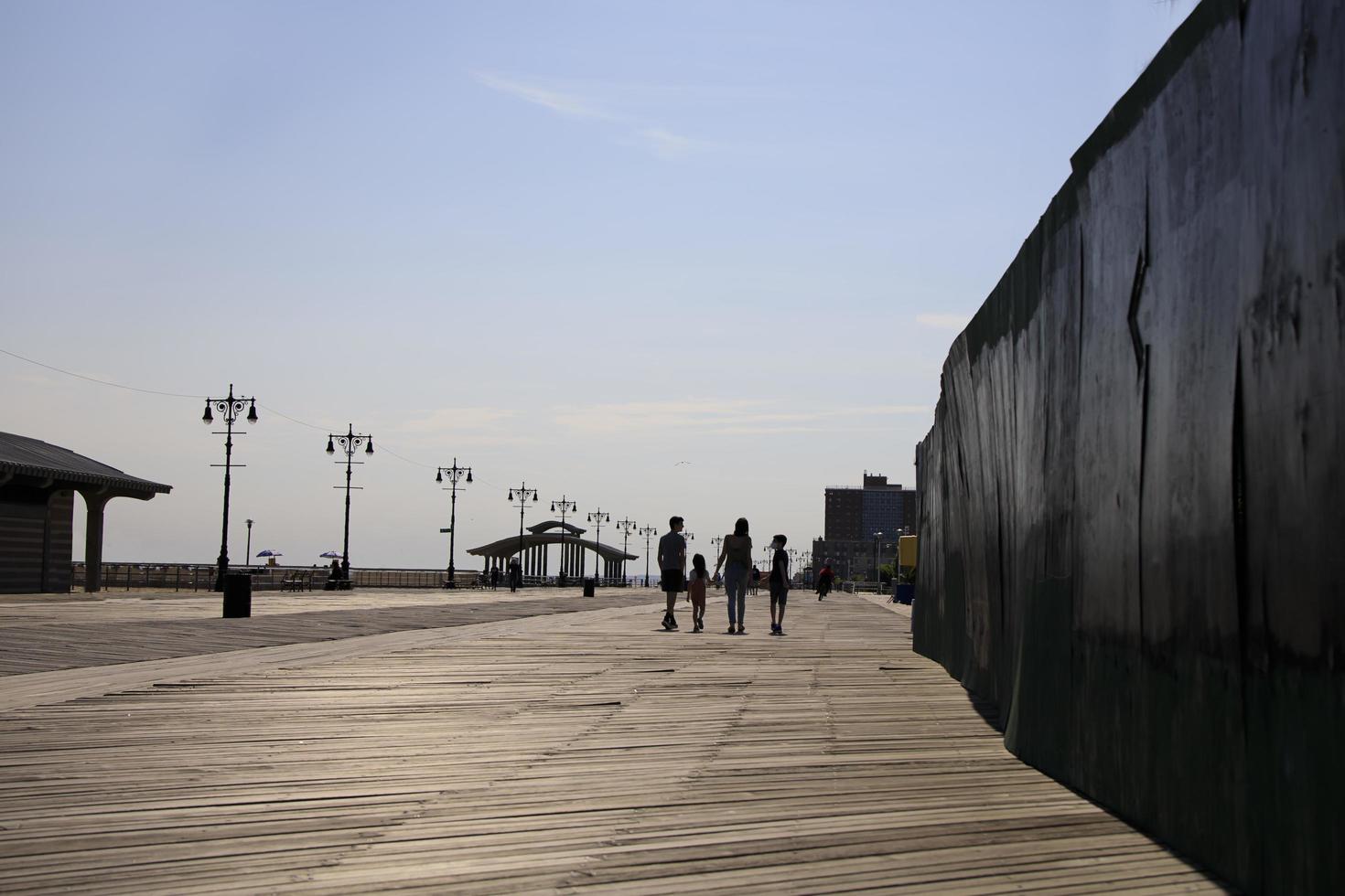 Silhouette of a family walking down a wooden boardwalk in summer photo