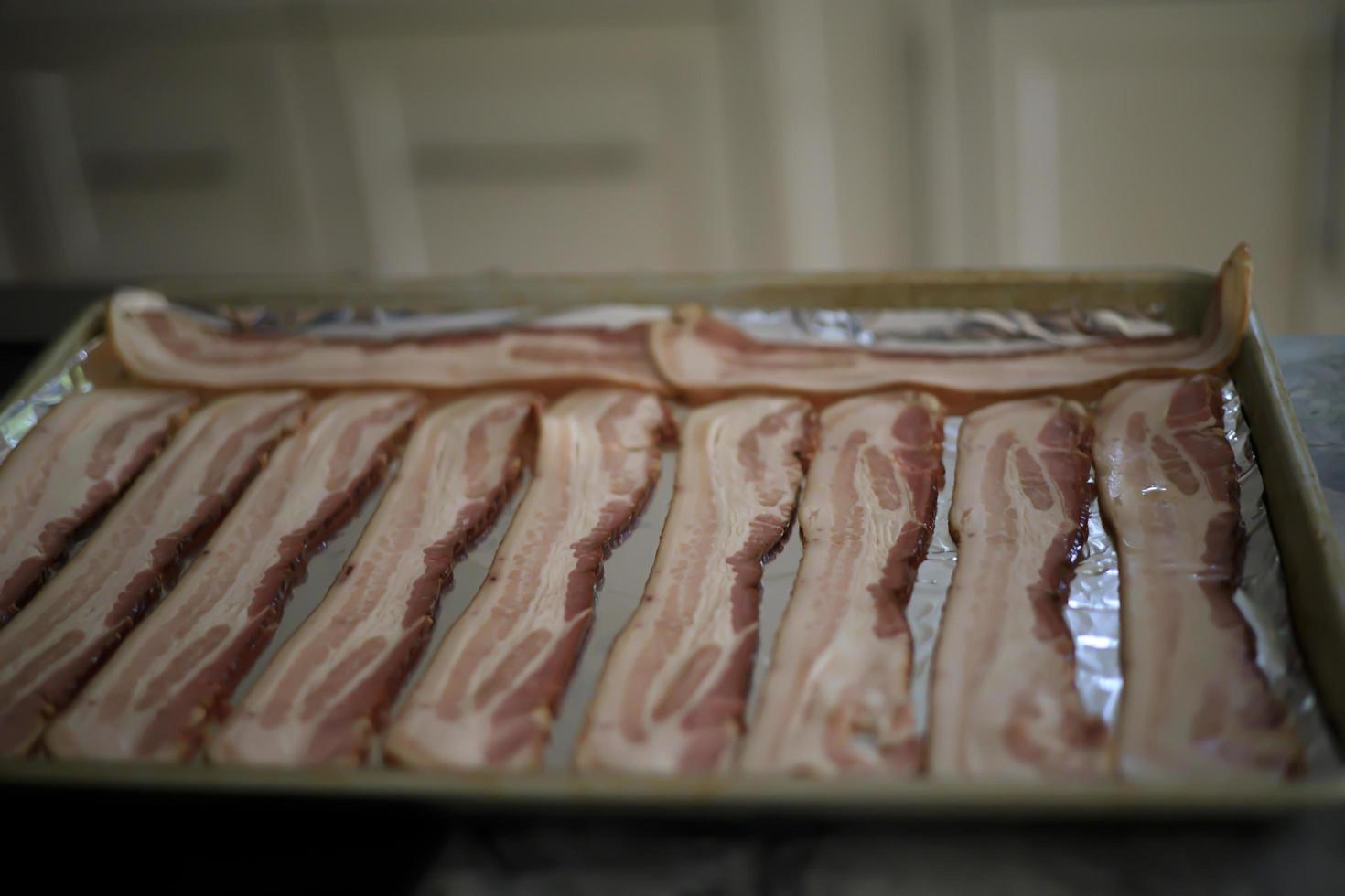 Strips of bacon sitting on a tray to be cooked photo