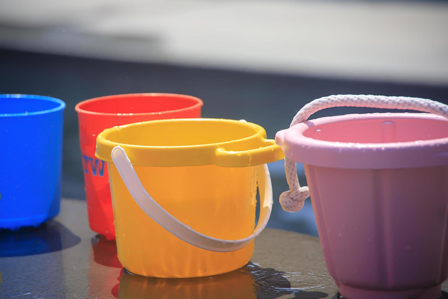 Colorful buckets filled with water by a pool photo