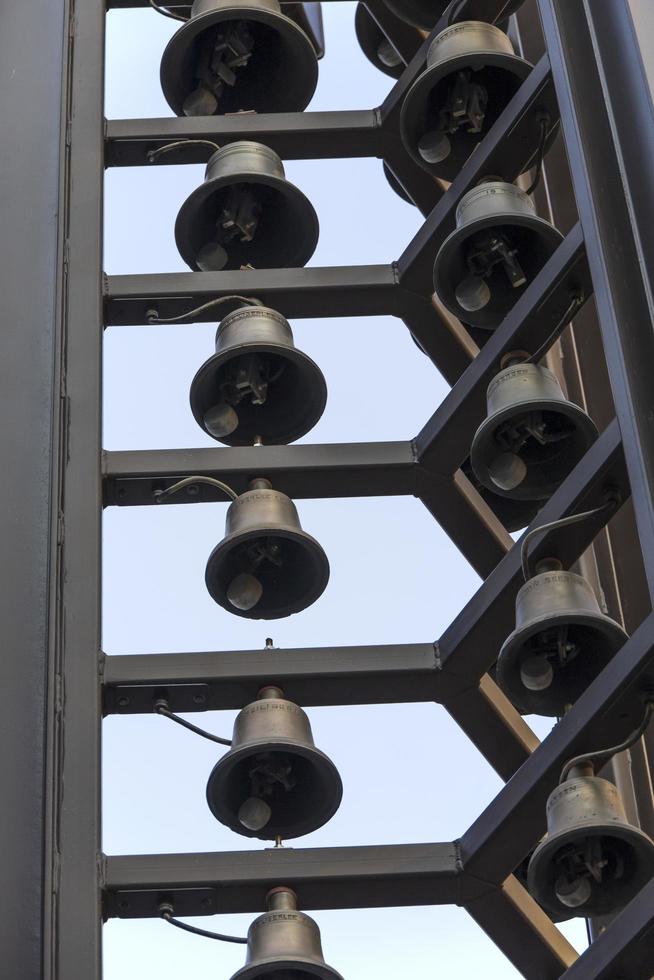 Rows of metal bells hanging from a building photo