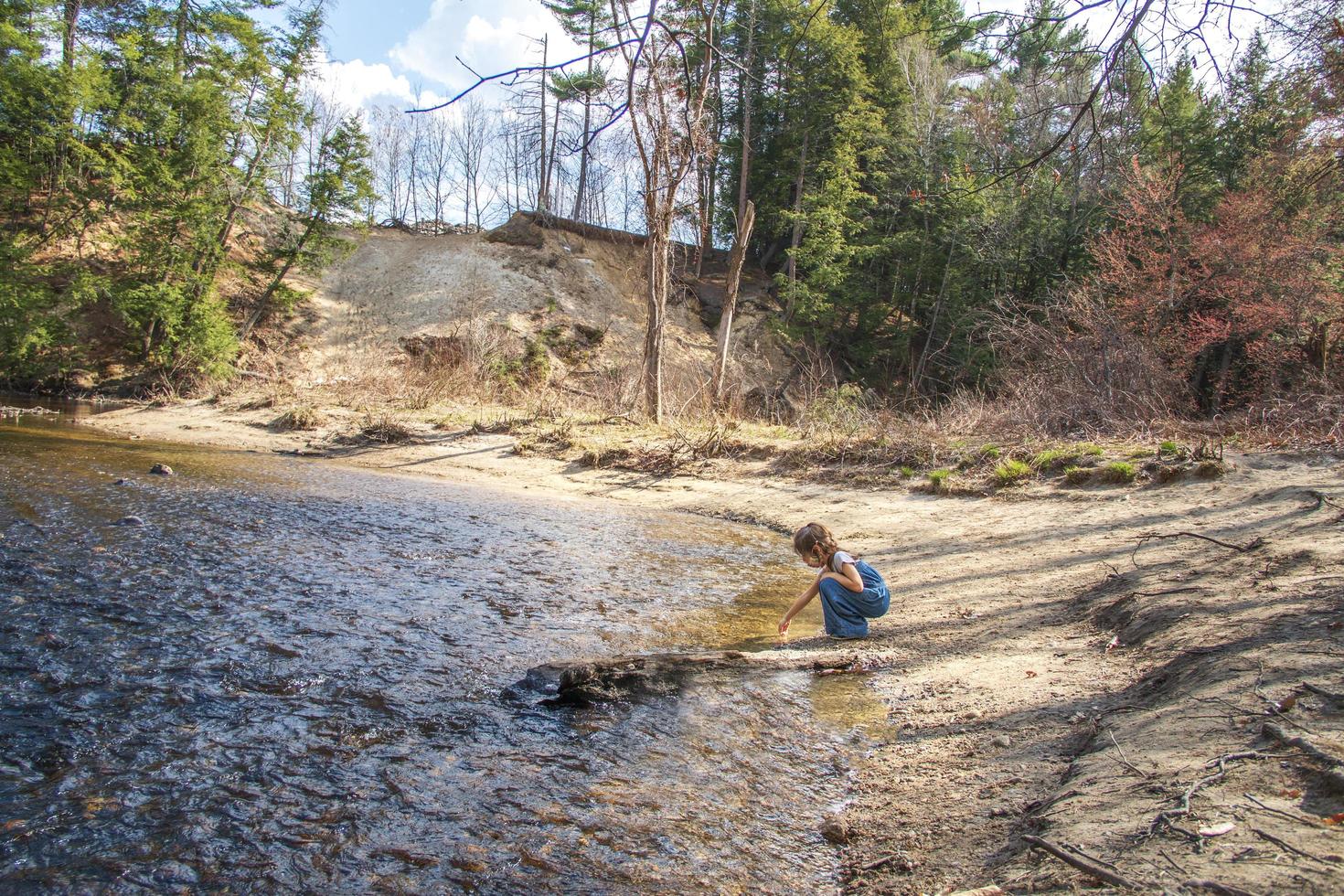 Child by the edge of a shore collecting rocks photo