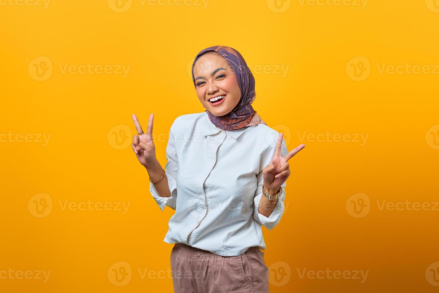 Portrait of cheerful Asian woman showing peace sign photo