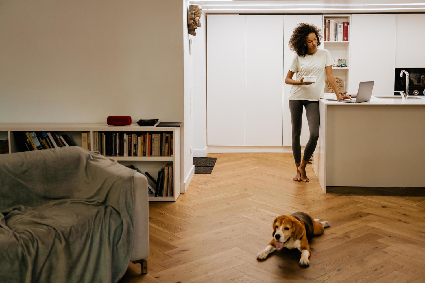 Joven negra desayunando mientras usa el portátil en casa foto