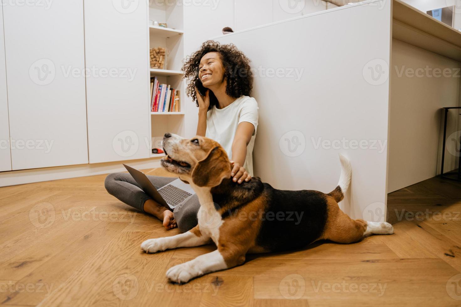 Black young woman talking on cellphone and playing with her dog photo