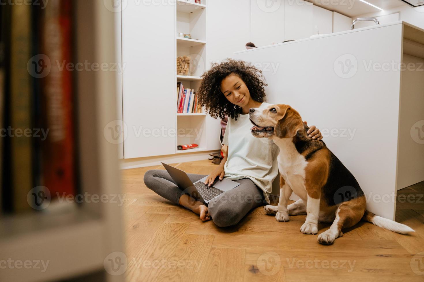 mujer joven negra usando laptop y acariciando a su perro foto