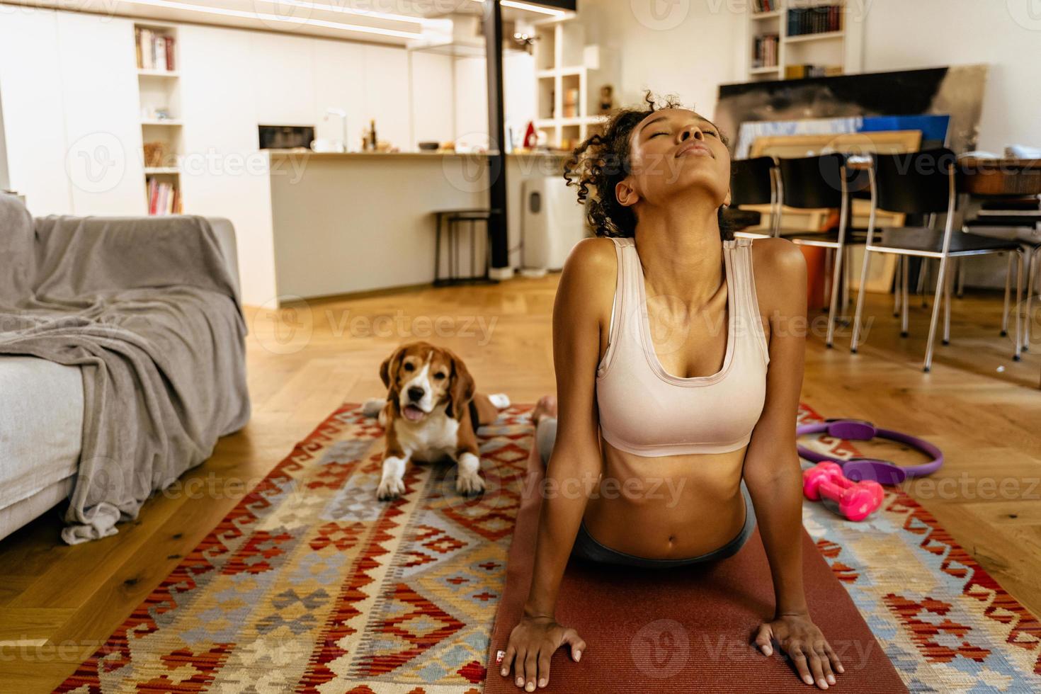Black young woman at home with dog doing exercises photo