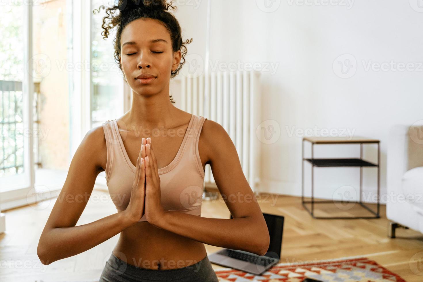 Joven negra meditando durante la práctica del yoga con su perro foto