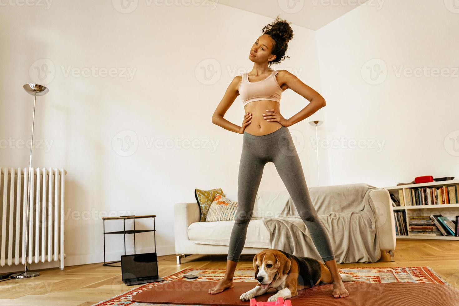 Black young woman doing yoga exercises with her dog during practice  photo