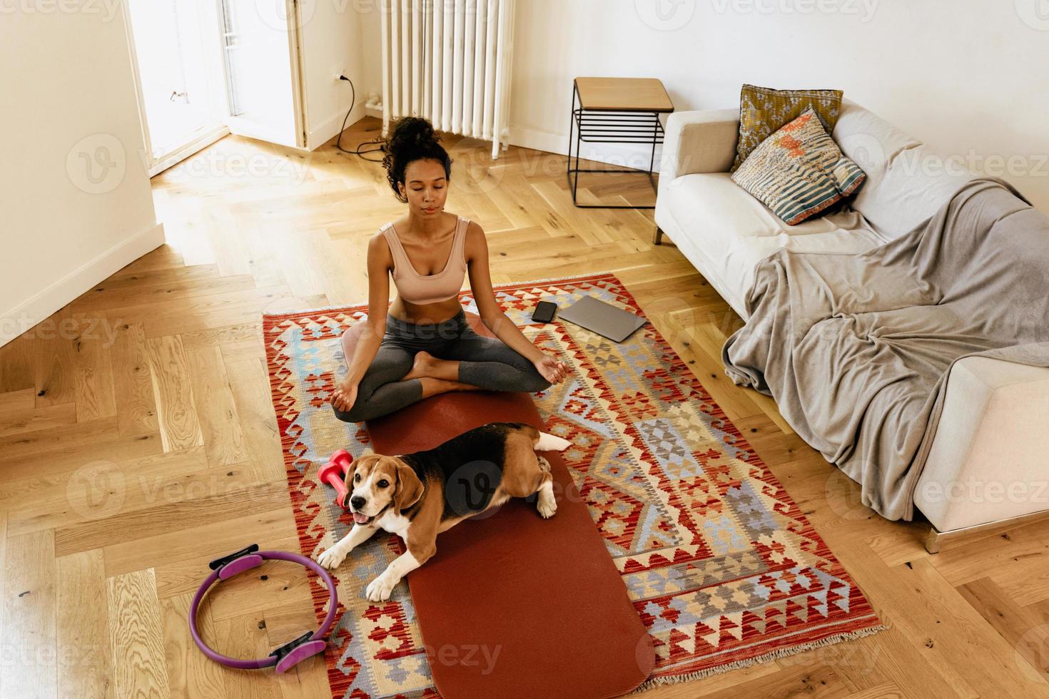 Joven negra meditando durante la práctica del yoga con su perro foto