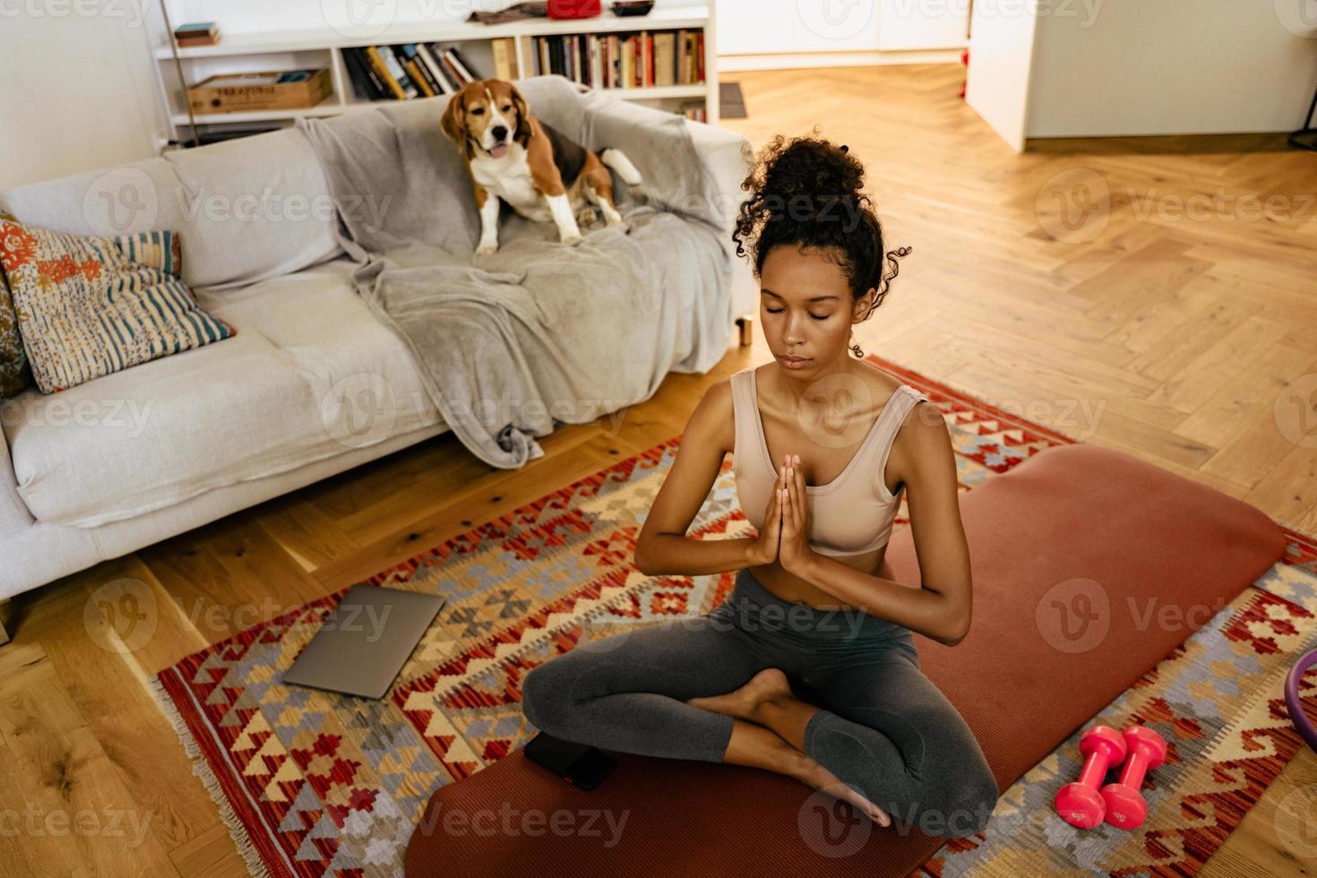 Joven negra meditando durante la práctica del yoga con su perro foto